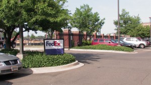 Outside view of FedEx o]board outside a house with parked cars